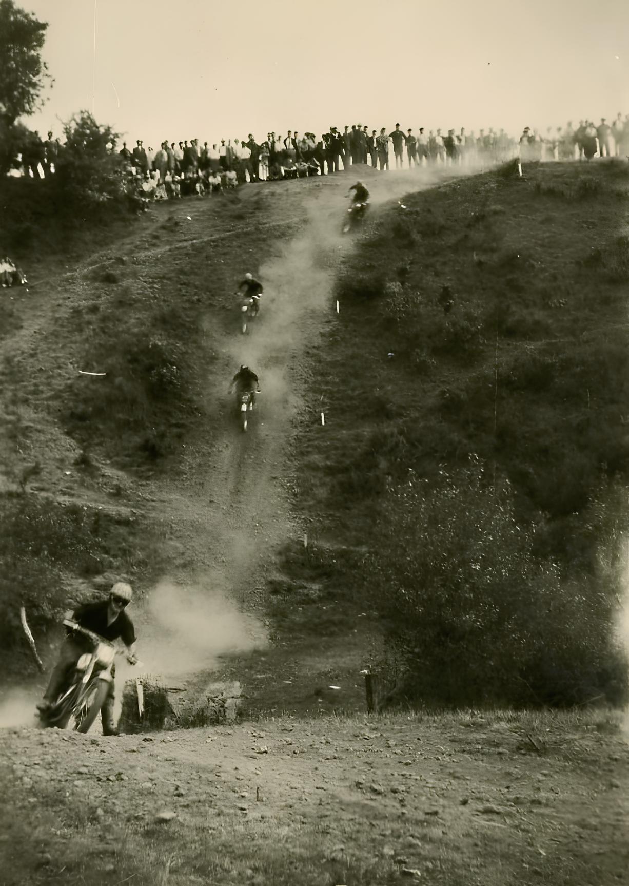 Moto-cross 1955 : Combes en tête dans la descente, suivi par le peloton.